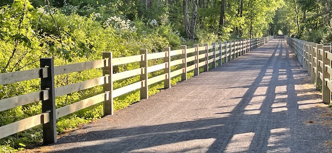 Rails to trails with 3 hole concrete fence posts on each side of the trail.